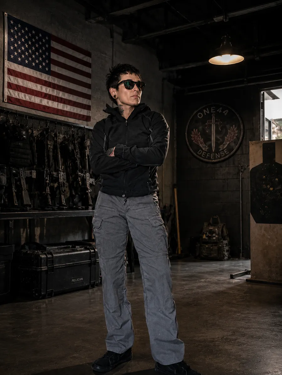 Alicia Mills in the armory beneath a US flag, with the ONE44 Defense emblem on the wall behind her
