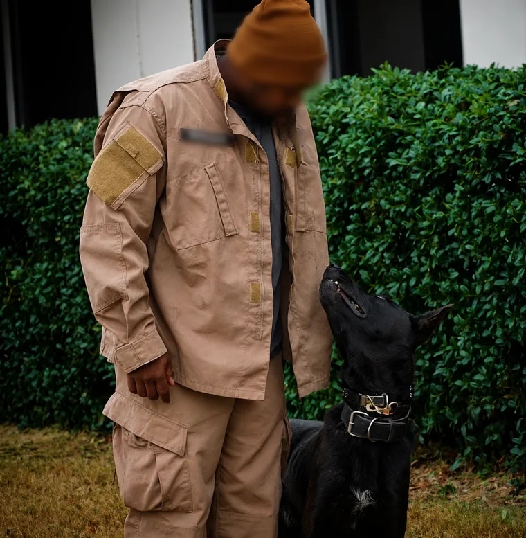 A handler and working K9 at heel, identifying details redacted